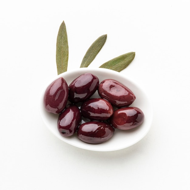 Photo gratuite olives pourpres sur plaque avec feuilles