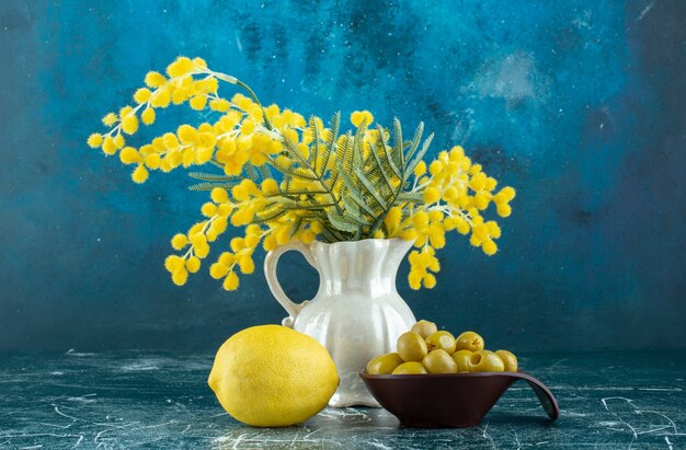 Olives vertes marinées dans une tasse noire avec un citron de côté. photo de haute qualité