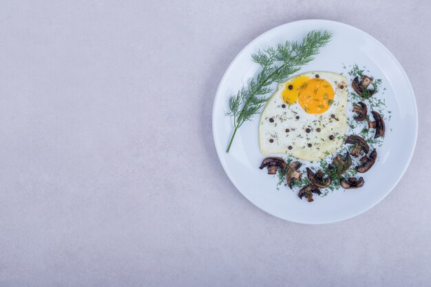 Omelette aux champignons frits sur plaque blanche.