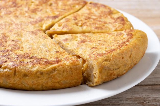 Omelette espagnole traditionnelle avec des ingrédients sur une table en bois.