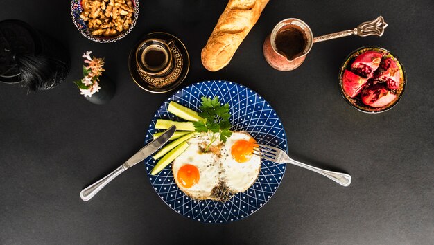 Omelette frite avec thé, pain et bol en noyer sur fond noir