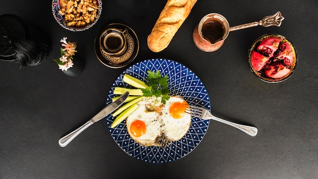 Omelette frite avec thé, pain et bol en noyer sur fond noir