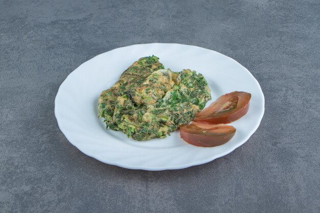 Omelette savoureuse aux verts sur plaque blanche.