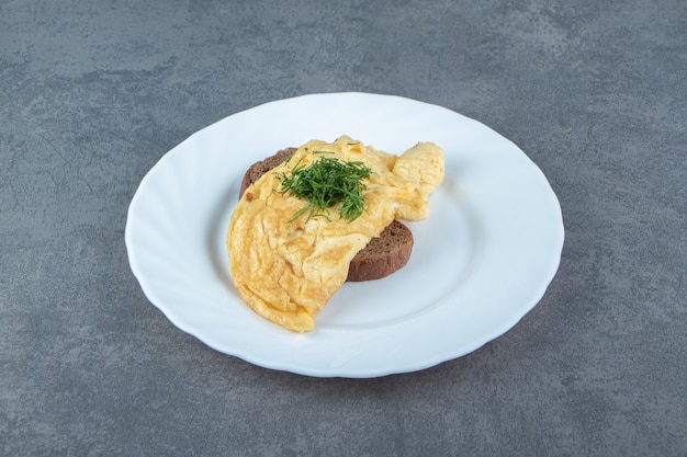 Omelette savoureuse avec du pain sur une plaque blanche.