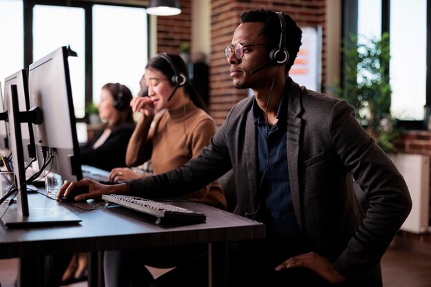 Opérateur répondant à l'appel téléphonique du client au service client, aidant les gens au support du centre d'appels. Réceptionniste masculin offrant une assistance de télémarketing sur la ligne d'assistance téléphonique au bureau.