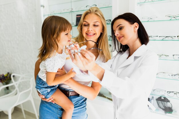 Opticien montrant le cadre de lunettes de petite fille