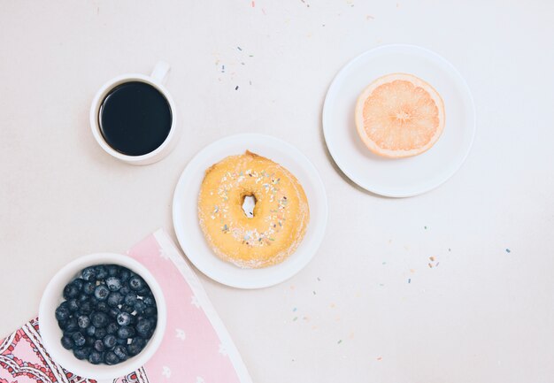 Orange coupées en deux; myrtilles; tasse à café et myrtilles sur fond blanc