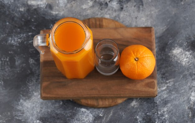 Orange, jus et verre vide sur planche de bois.