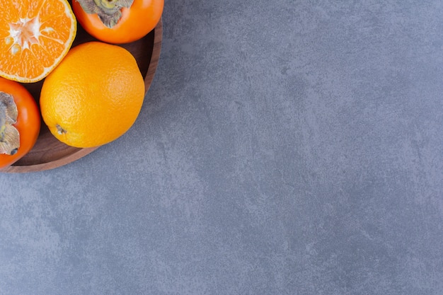 Orange et kaki sur plaque de bois sur table en marbre.