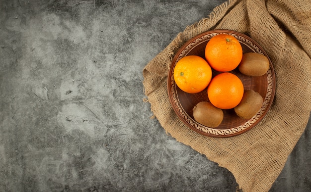 Orange et kiwis dans un bol en poterie. Vue de dessus.