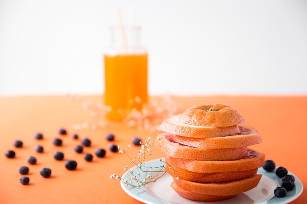 Orange mûre coupée en tranches avec des myrtilles et une fleur de gypsophila sur un fond coloré