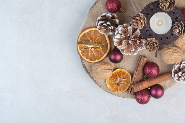 Photo gratuite orange séchée avec des pommes de pin et des boules de noël sur une plaque en bois. photo de haute qualité