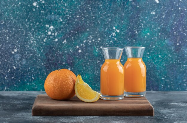 Orange en tranches et jus sur planche de bois.