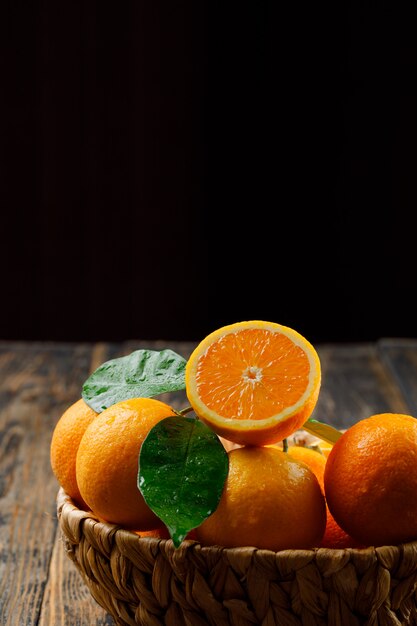 Oranges de bon goût dans un panier en osier avec des feuilles