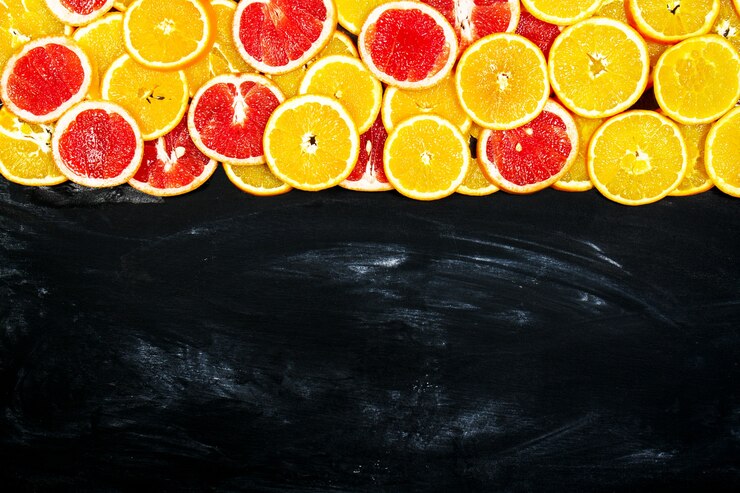 Photo gratuit oranges coupées en tranches sur une ardoise noire