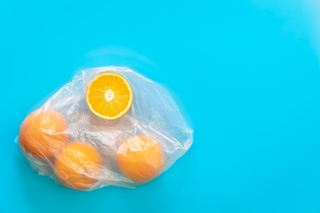 Oranges dans un sac en plastique isolé sur plat bleu