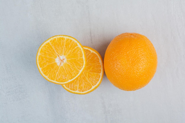 Oranges entières et demi-coupées fraîches sur fond de pierre. photo de haute qualité