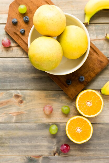 Oranges entières; les raisins; banane et myrtilles sur fond en bois