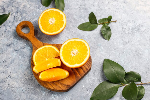 Oranges fraîches en tranches sur une planche à découper sur une surface en béton