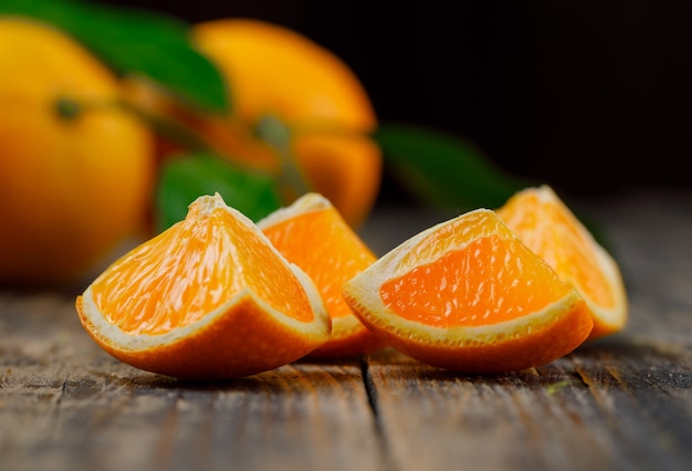 Oranges avec des tranches et vue latérale de la branche sur une table en bois et noir