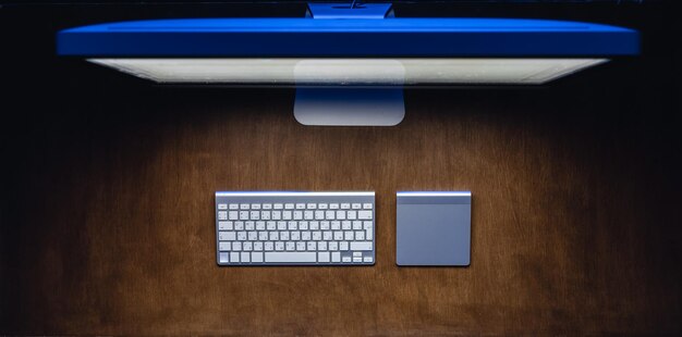 L'ordinateur et le clavier sur une table en bois la nuit vue du haut