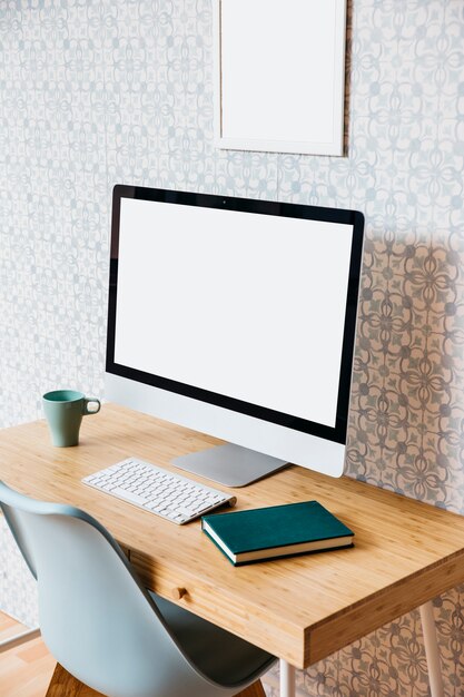 Ordinateur avec écran blanc blanc et agenda sur bureau en bois