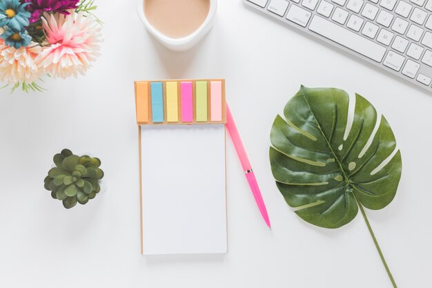 Ordinateur portable avec des autocollants près de tasse à café, clavier et plantes