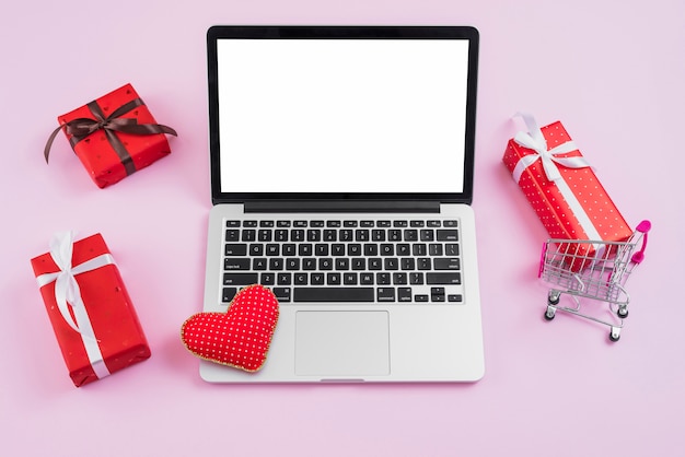 Photo gratuite ordinateur portable avec coeur fait à la main au milieu de cadeaux et de panier