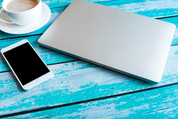 Un ordinateur portable gris sur une table en bois bleu