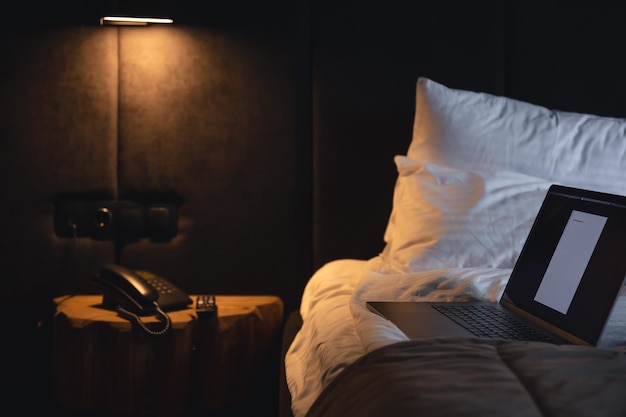 Ordinateur portable sur le lit la nuit à l'intérieur de la chambre