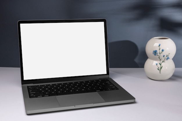 Un ordinateur portable minimal et un vase à fleurs