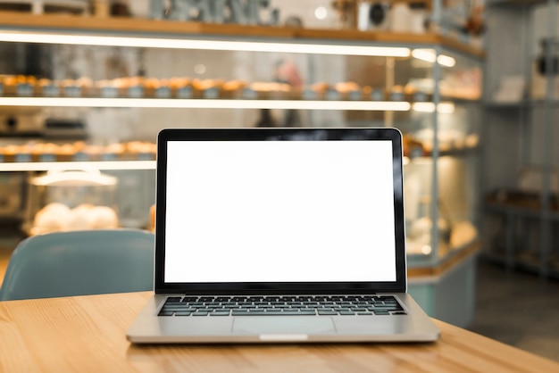 Un ordinateur portable ouvert avec un écran blanc sur une table dans un café