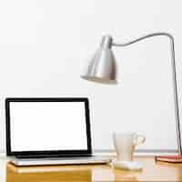 Photo gratuite ordinateur portable près d'une tasse, d'une lampe et d'une souris d'ordinateur