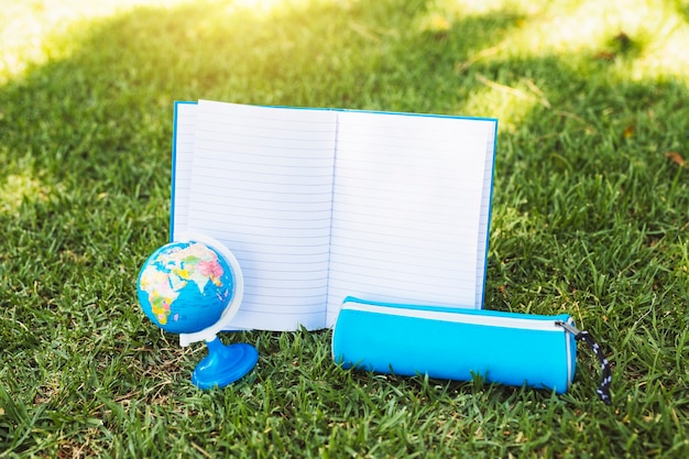 Ordinateur portable près de trousse et globe sur l&#39;herbe