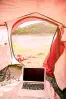 Photo gratuite ordinateur portable sous tente sur la plage