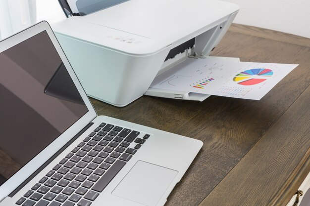 Ordinateur portable sur une table en bois avec une imprimante