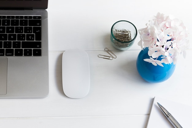 Ordinateur portable et vase bleu à fleurs roses sur le bureau au lieu de travail