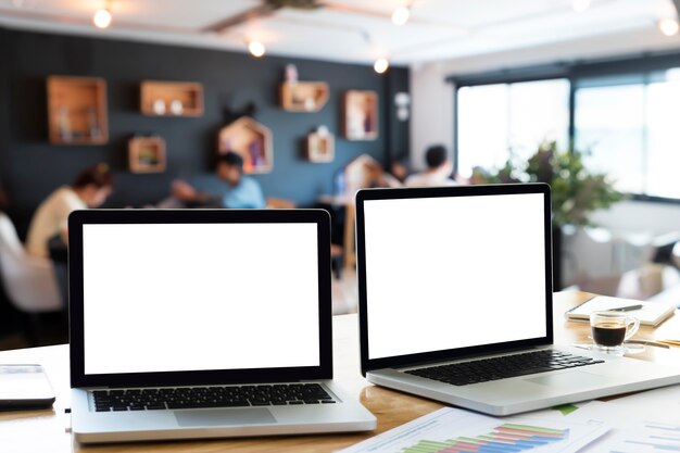 Les ordinateurs portables sur le bureau dans le bureau avec la lumière du matin et le flou de l&#39;équipe d&#39;affaires discusLaptops sur le bureau dans le bureau avec la lumière du matin et le contexte de discussion de l&#39;équipe commerciale flou