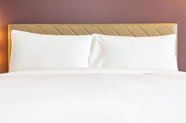 Oreiller et couverture confortables de couleur blanche sur le lit