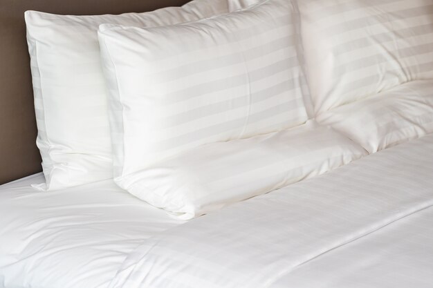 Oreillers confortables blancs sur le lit avec couverture