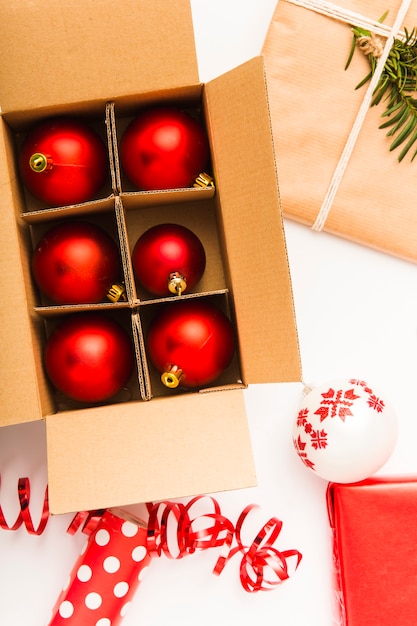 Photo gratuite ornements de noël rouges dans une boîte en carton et un cadeau