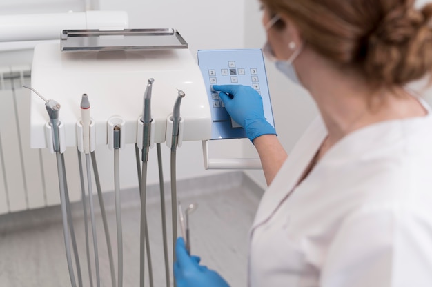 Photo gratuite orthodontiste féminin avec des gants en latex manipulant du matériel dentaire