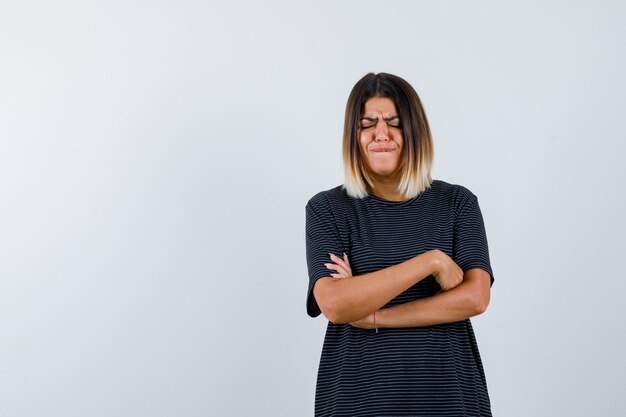 Ortrait de dame debout avec les bras croisés en t-shirt noir et à la vue de face en détresse