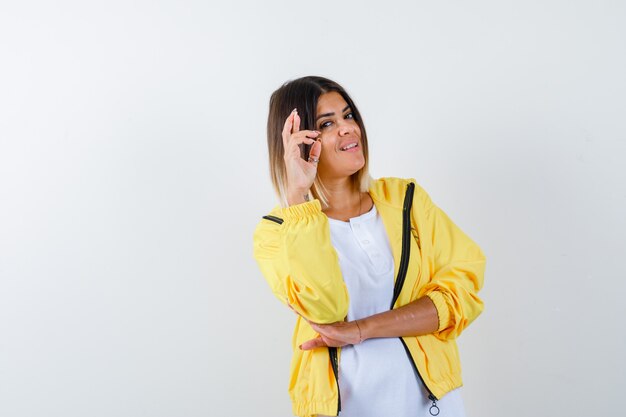 Ortrait de dame en gardant les doigts croisés en t-shirt, veste et à la vue de face joyeuse