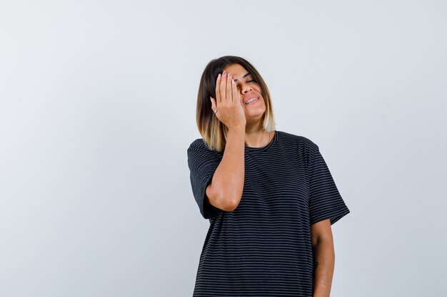 Ortrait de jeune femme tenant la main sur la joue tout en fermant les yeux en robe polo et à la jolie vue de face