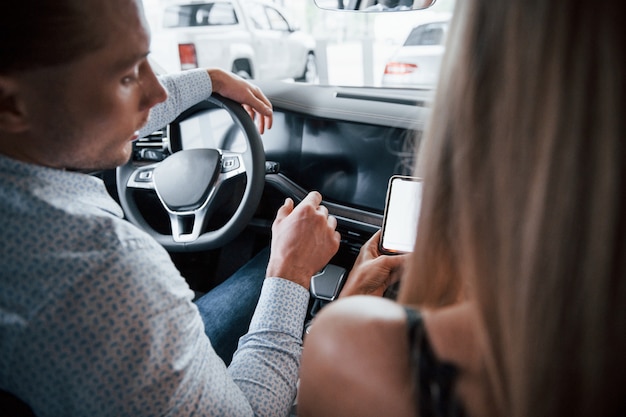 Où allons-nous. Gestionnaire positif montrant les caractéristiques de la nouvelle voiture à une cliente