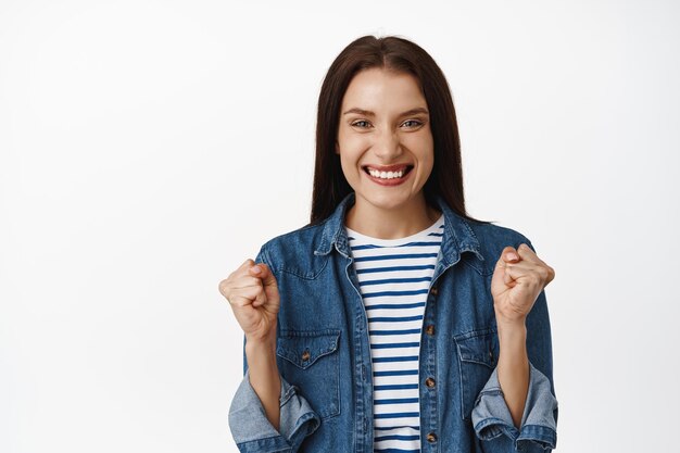 Oui je l'ai fait. Femme adulte réussie célébrant la victoire, serrer le poing et souriant excité, gagnant la compétition, triomphant de la victoire et de la joie, atteindre l'objectif, debout sur fond blanc