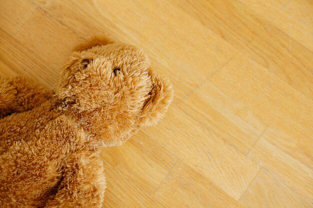 Ours en peluche mignon brun sur le plancher en bois