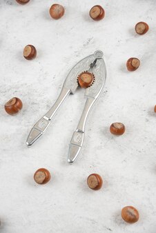 Outil de craquage des noix avec des noisettes décortiquées éparses sur une table en marbre.