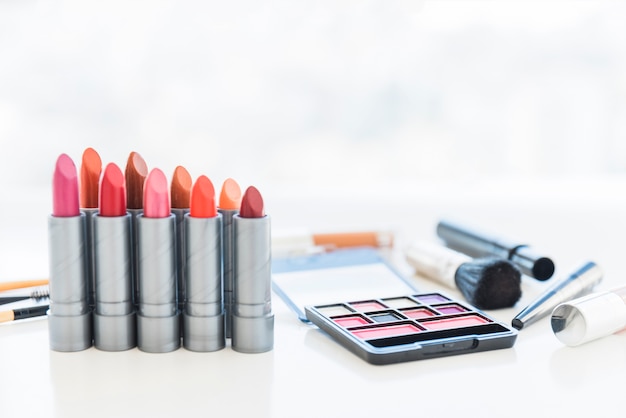 Outils de maquillage professionnels avec une palette d&#39;ombres à paupières cosmétiques et une rangée de nuances de rouge à lèvres